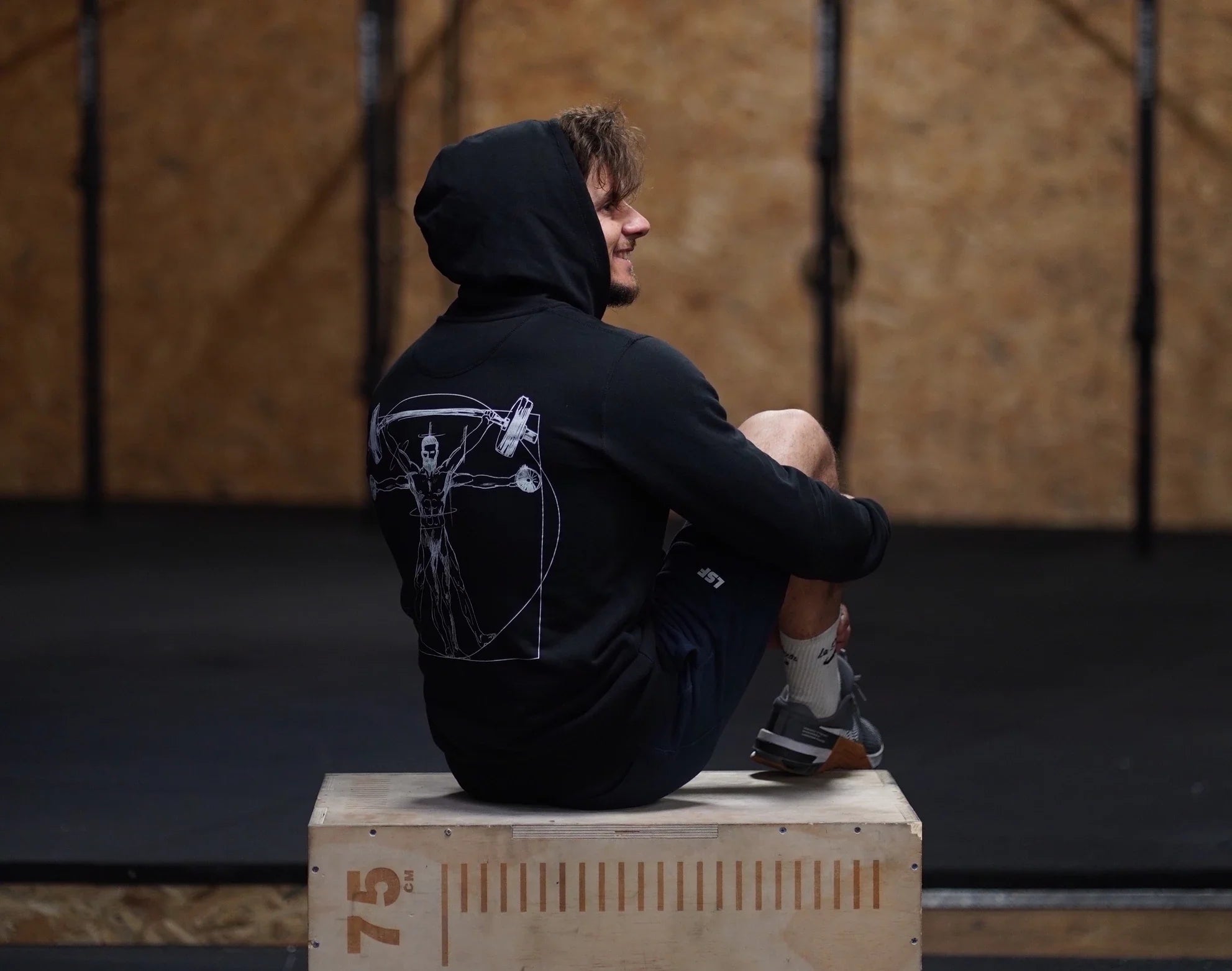 Homme en sweat-shirt de sport dans une salle de CrossFit 